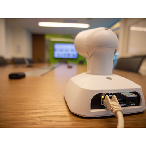 White electronic device with a cable on a wooden surface, blurred office background