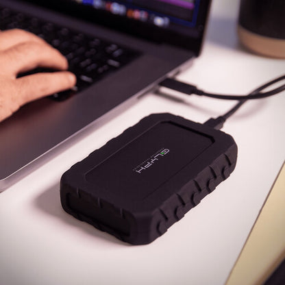 Black external hard drive connected to a laptop on a desk