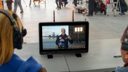 Person on a monitor in a room with other people and equipment