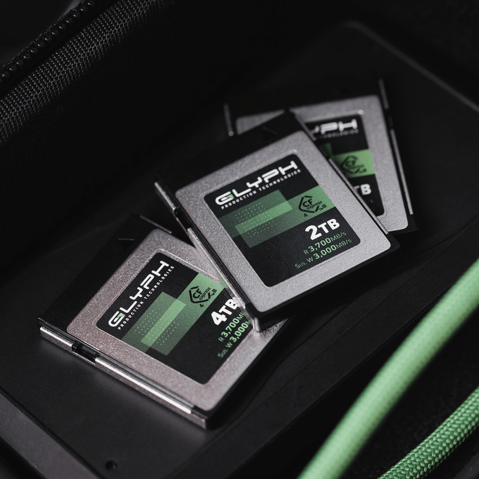 Three Glyph CFexpress memory cards with green and black labels on a dark surface.