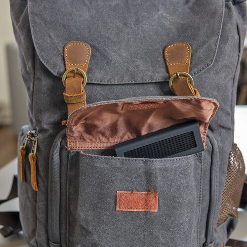 Gray backpack with brown leather straps and pocket, containing a black device.