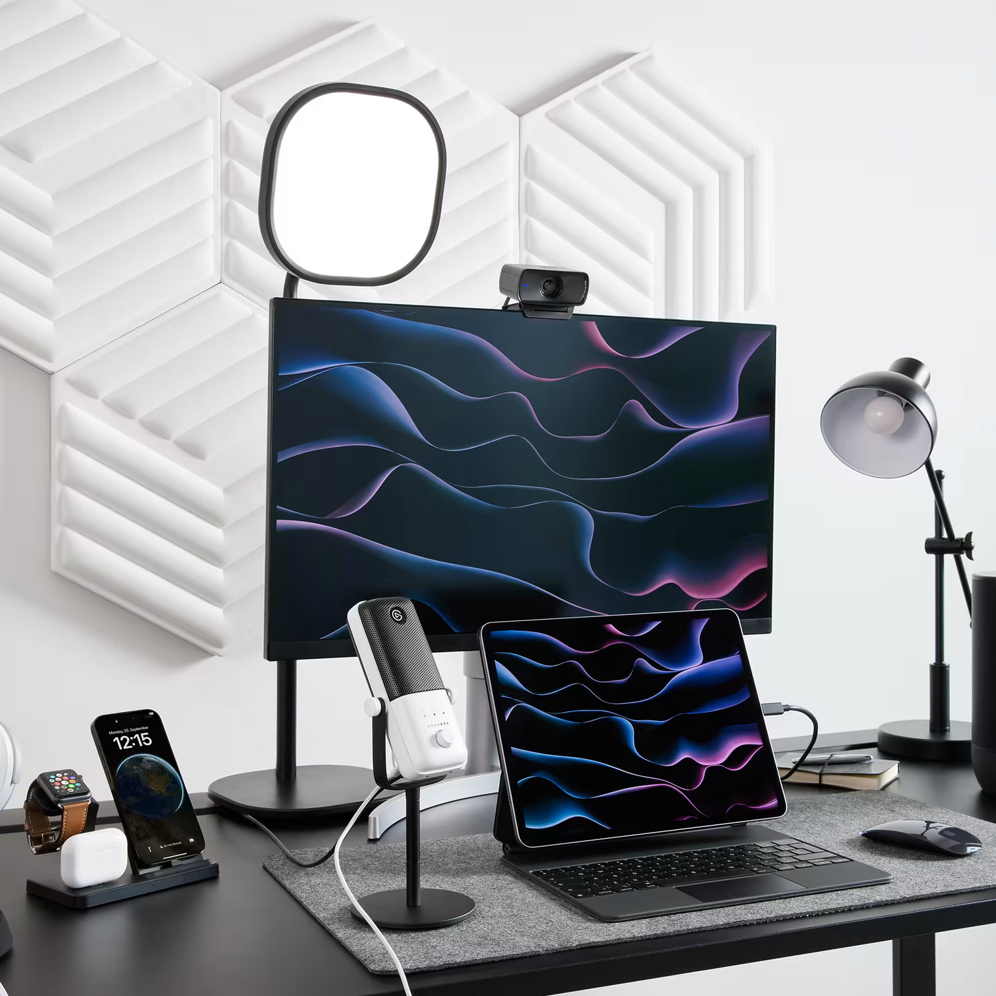 Modern office desk setup with computer monitor, laptop, and accessories on a white wall background.
