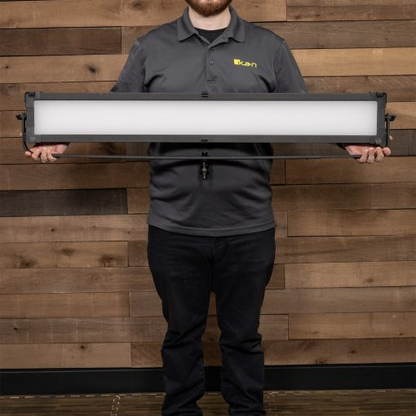 Person holding a large rectangular light fixture against a wooden background