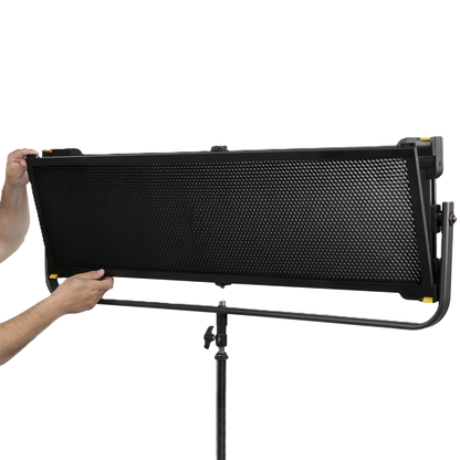 Person holding a large black light panel on a stand against a white background