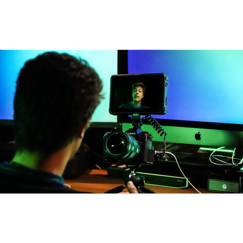 Person using a camera to record themselves on a computer screen with a green screen background