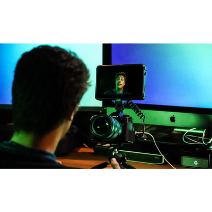 Person using a camera to record themselves on a computer screen with a green screen background