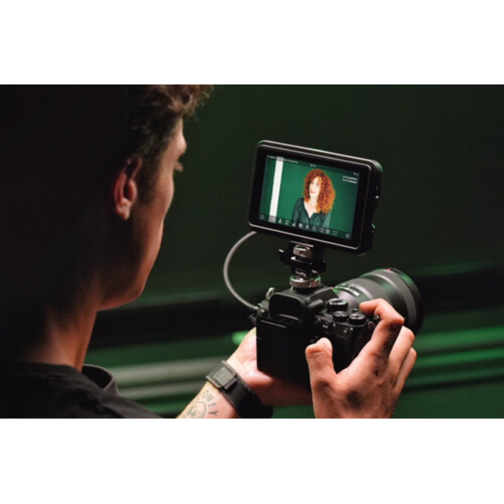 Person holding a camera with a screen displaying a person's face, against a dark background